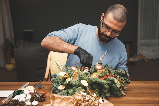 Man versieren van een kerstkrans Kerstboom krans decoratie met man hand workshop DIY