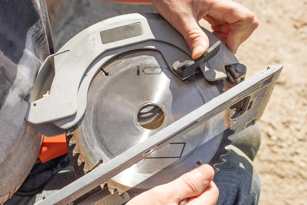 Man vervangt het zaagblad van een elektrische verstekzaag voor houtbewerking. reparatie en onderhoud van elektrisch gereedschap.