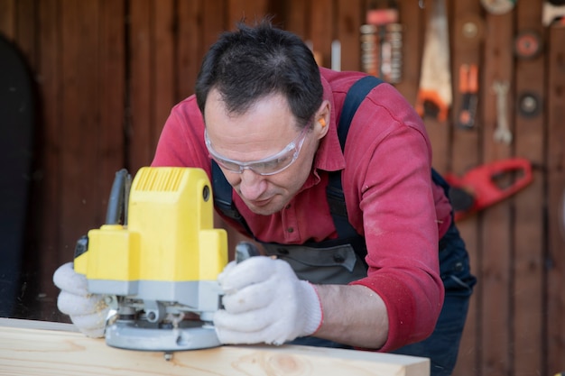 Man verwerkt hout met fraser in de werkplaats van het landhuis