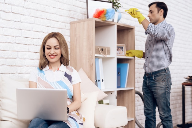 Man verwijdert stof van plank en vrouw in bank.