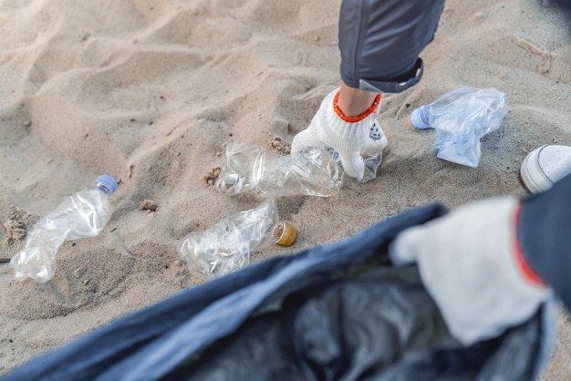 Man verzamelt plastic van het strand in tas Ecologisch beschermingsconcept