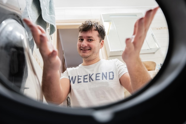 Man view from washing machine inside Male does laundry daily routine Satisfied expression on his face spreading hands to the side