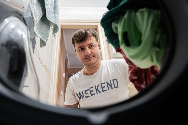 Man view from washing machine inside Male does laundry daily routine