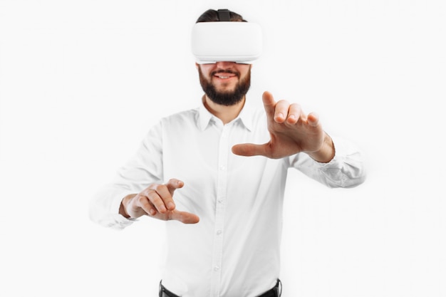 A man in virtual glasses, presses his finger on an empty space on a white wall