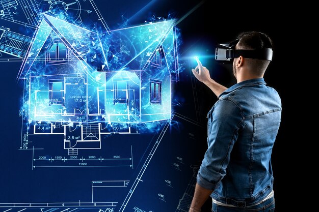 A man in virtual reality glasses designs a building a hologram of a house