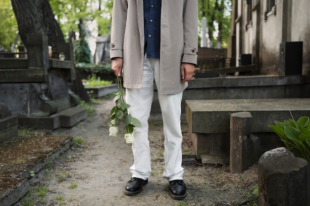 man visiting the cemetery with white roses