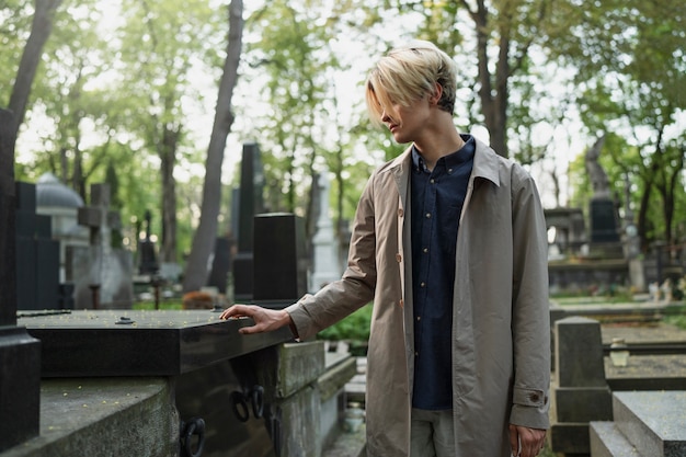 Foto uomo che visita una tomba al cimitero