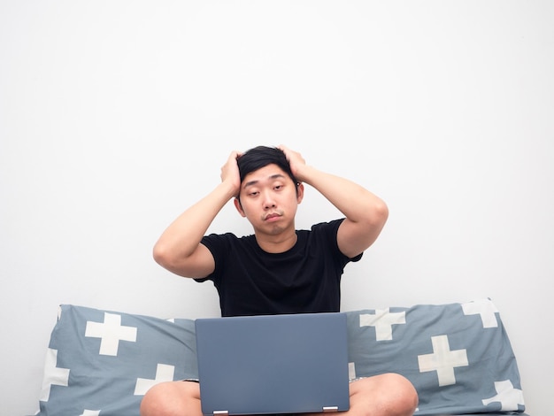 Man voelt zich slaperig en zit op bed met laptop