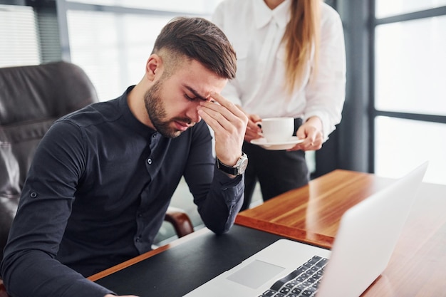 Man voelt zich slecht vrouw en man in formele kleren werken samen binnen in het kantoor bij tafel