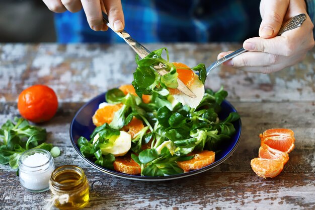 Man voorbereiding van verse salade op een bord