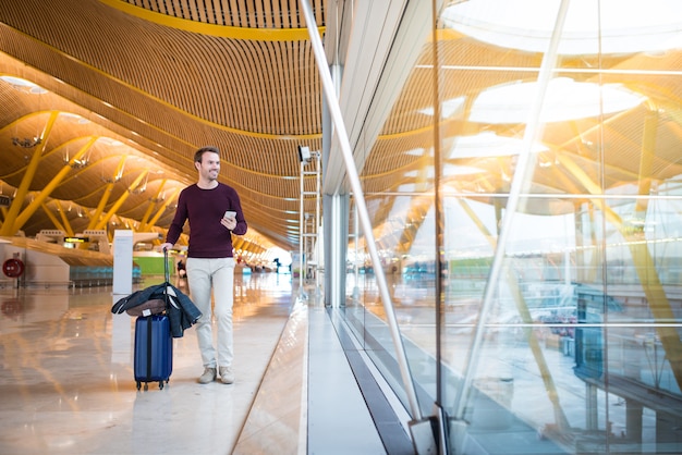 Man voorkant lopen op de luchthaven met behulp van de mobiele telefoon