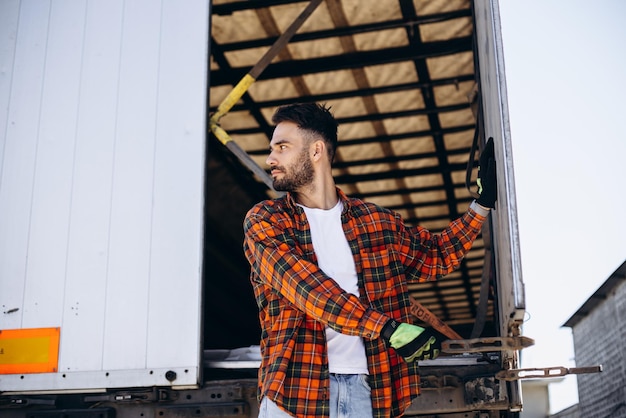 Man vrachtwagenchauffeur staat bij zijn vrachtwagen