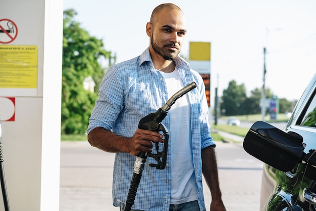 Man vullen benzine brandstof in auto bij tankstation