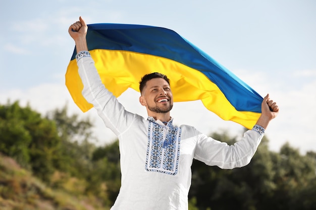 man in vyshyvanka with flag of ukraine outdoors