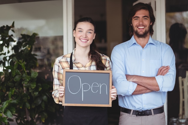 Man and waitress holding chalkboard with open sign