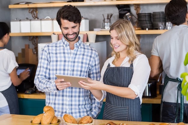 Man and waitress standing at counter using digital tablet