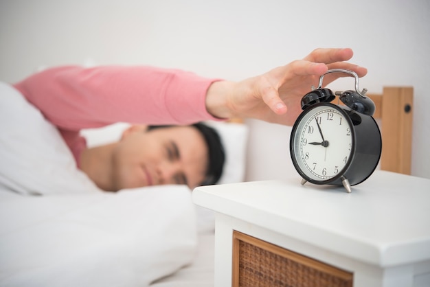 Man wake up doing turn off alarm clock in the morning