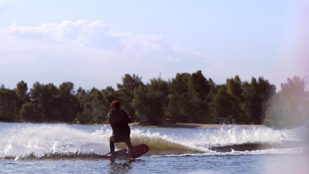 Man wakeboarding on waves Water skiing on lake behind boat Wakeboarder surfing