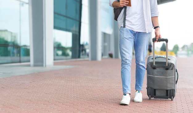 Uomo che cammina verso l'aeroporto con i bagagli a bordo