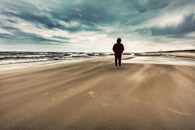 風の強い嵐の日に浜辺を一人で歩く男