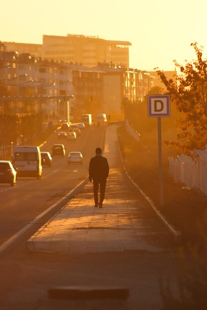 A man walking alone with his back turned at sunset