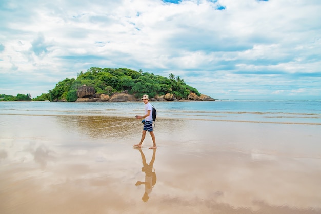 A man walking along the beach of Sri Lanka.