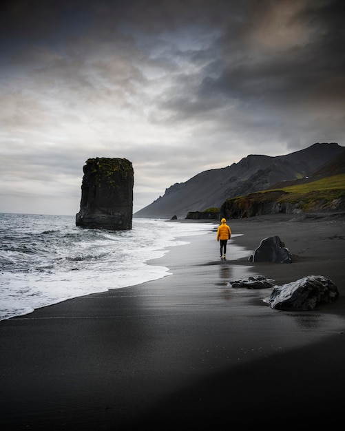 Человек идет по черному пляжу в Исландии