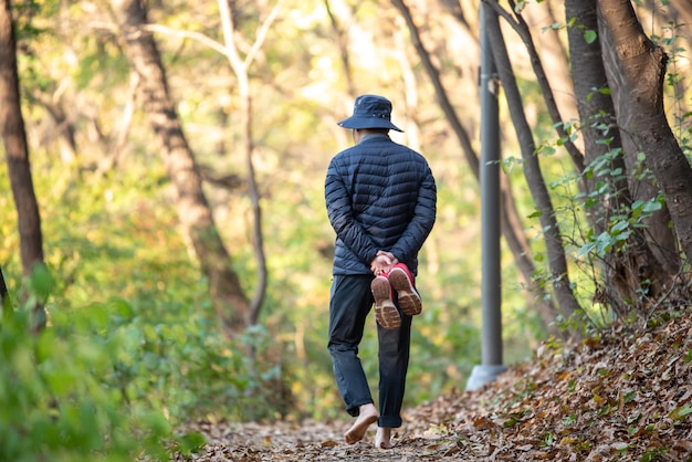 Foto un uomo che cammina a piedi nudi su una strada ricoperta di foglie concept di stile di vita sano