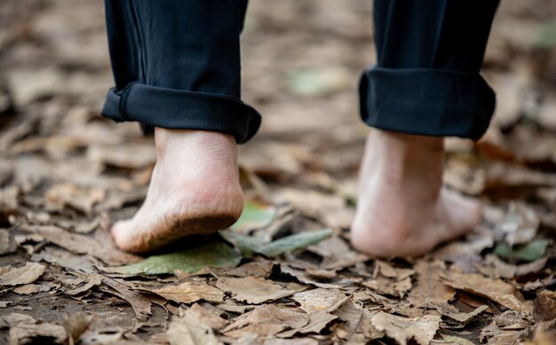 Foto un uomo che cammina a piedi nudi su una strada ricoperta di foglie concept di stile di vita sano