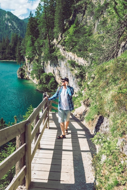 Foto uomo che cammina lungo il sentiero escursionistico intorno al lago di braies in italia montagne dolomitiche