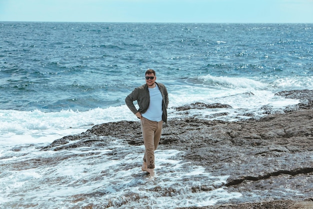 Man walking by rocky beach in windy day summer vacation enjoy sea view