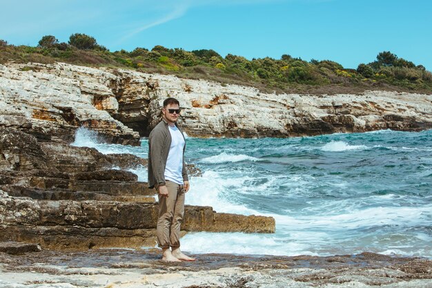 Man walking by rocky beach in windy day summer vacation enjoy sea view