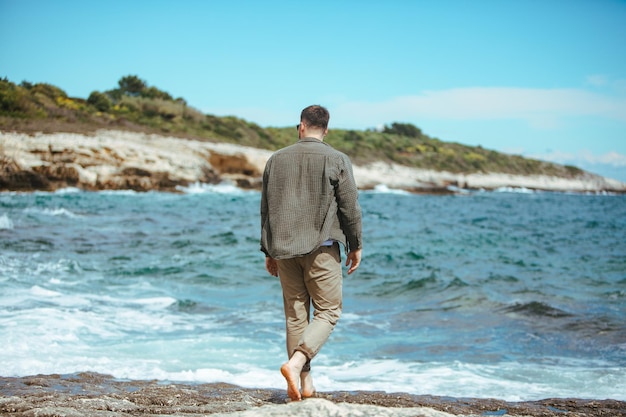 Man walking by rocky beach in windy day summer vacation enjoy sea view