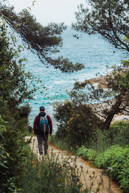 Man walking by trial to sea beach overcast weather