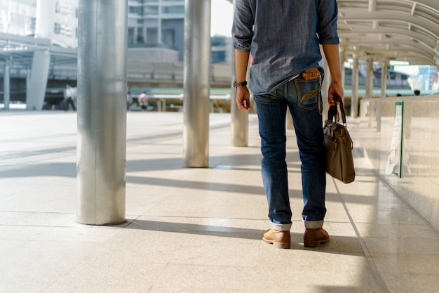 Uomo che cammina in città e in possesso di borsa per laptop