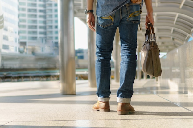 都市で歩いてラップトップバッグを持っている男