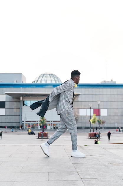 Man walking in the city putting on his jacket