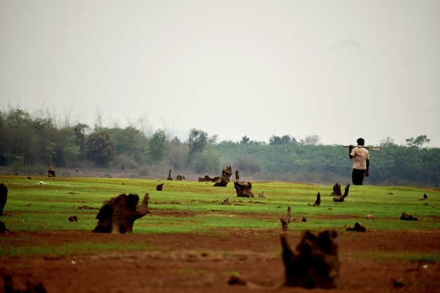 Photo man walking on field against sky