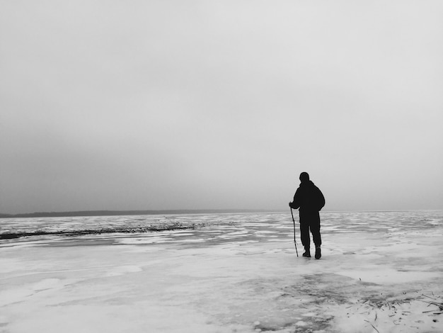 Foto uomo che cammina sul ghiaccio ghiacciato contro il cielo