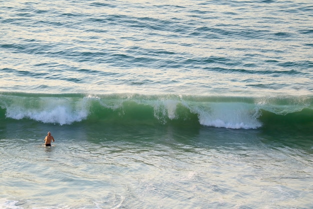 Man walking into a big waves of Atlantic ocean at Copacabana beach in Rio de Janeiro, Brazil