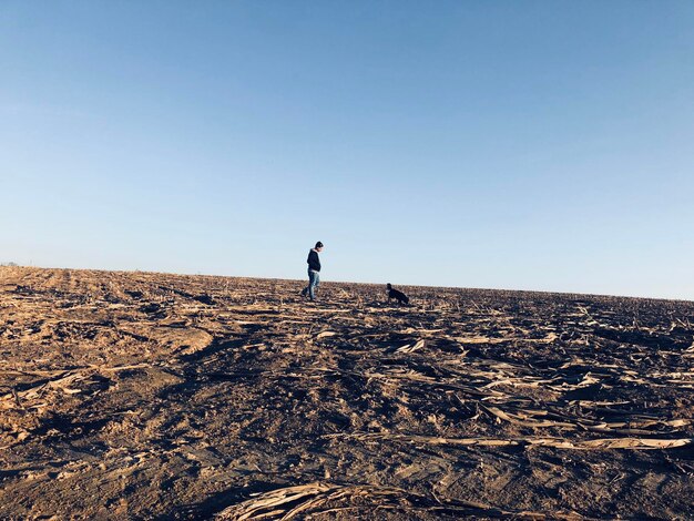 Photo man walking on land against clear sky