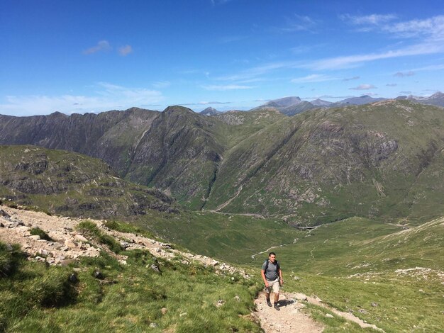 青い空を背景に山を歩く男