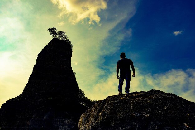 写真 天に向かって岩の上を歩く男