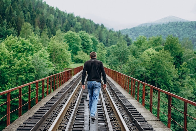 森の中の鉄道橋の上を歩く男