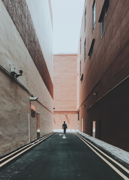 Photo man walking on road amidst buildings