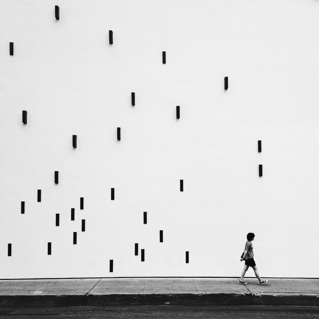 Man walking on sidewalk by artistic wall