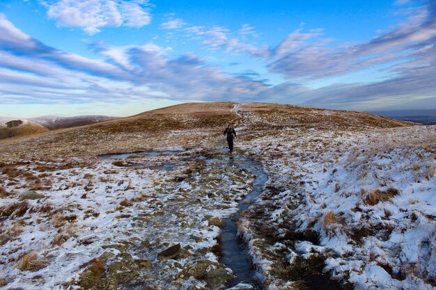 Photo man walking over stream amidst snow covered landscape