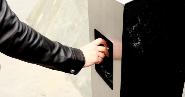 Photo man walking on the street and throwing garbage to a trash bin.