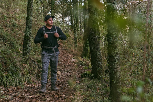 Man walking through a forest wearing a backpack