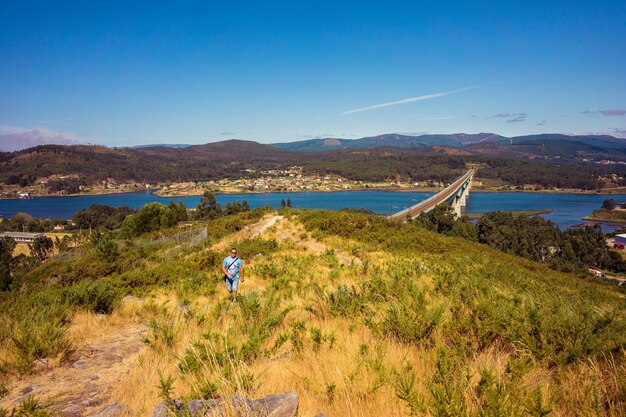 Man walking to the top of a mountain with the train tracks on the foreground person